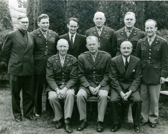 Some of the many personnel who worked in the Signal Intelligence Service in Arlington Hall, during World War II. Standing left to right: Mr. Mark Rhoads; Colonel Kullback; Mr. John Hurt; Unknown; Colonel Rowlett; Colonel Sinkov; Colonel M. Grail; Colonel Corderman; William F. Friedman